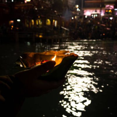 devotee holding aarti flower pot for ganges river evening prayer at night